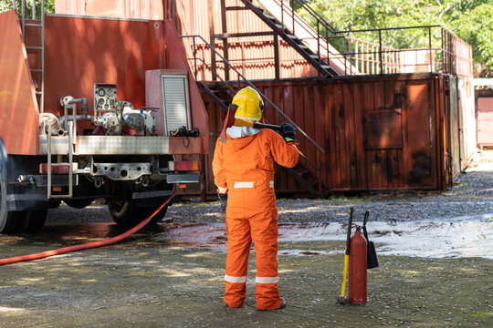 Firefighters wearing helmets with fire safety equipment Use Twirl aerosol fire extinguishers to fight oil flames.Preventing fire accidents is an industrial safety concept.