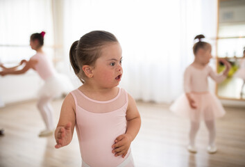 Little girl with down syndrome at ballet class in dance studio. Concept of integration and...