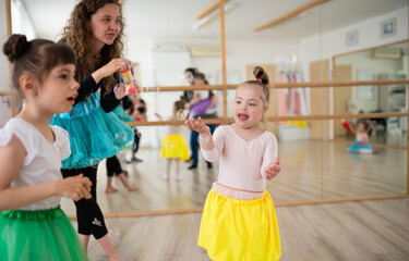 Little girls with down syndrome and dance lecturer having fun in ballet school studio.