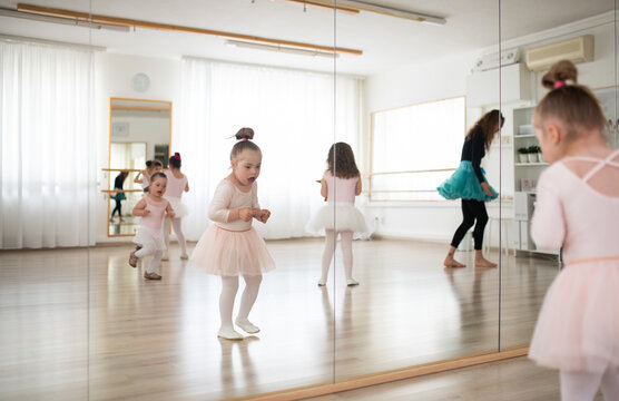 Little girls with down syndrome dancing ballet in ballet school studio.