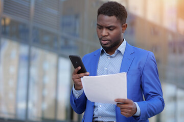 African American businessman examines monthly paper report of business. Black entrepreneur...