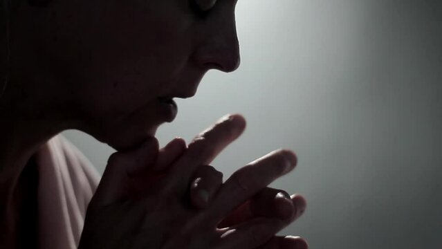 Woman praying to god with hands together on grey background stock footage
