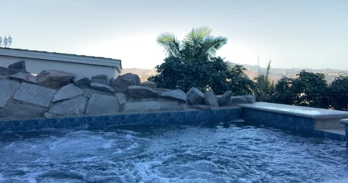 Hot Tub Bubbles in Beautiful Pool with Palm Trees &bull;&nbsp;Luxury Vacation Home Landscaping &bull; Stationary Shot in Horizontal