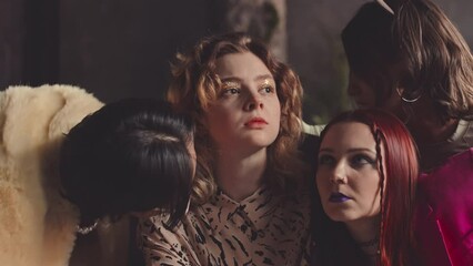 Slowmo of eccentric team of glamorously dressed vogue dancers looking seductively at camera and making tempting movements with their arms, dancing together in dark studio