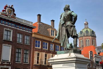 Fototapeta na wymiar Close-up on the statue of Jan Pieterszoon Coen (1587, 1629), historic houses and the Dome of Koepelkerk church in Hoorn, West Friesland, Netherlands. The statue was unveiled in 1893.