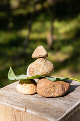 A pyramid of four small stones stands on a wooden pole on a forest road