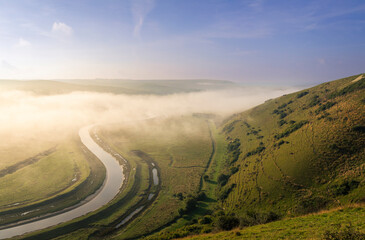 Misty morning view from High and Over of the Cuckmere river and valley leading down to the coast and Cuckmere Haven on the south downs east Sussex south east England UK