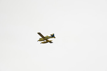 Firefighting seaplane flying through a clear sky before pouring water on the fire. Aerial firefighting.