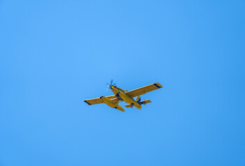 Fototapeta na wymiar Firefighting seaplane flying through a clear sky before pouring water on the fire. Aerial firefighting. Point of view from below.