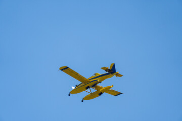 Firefighting seaplane flying through a clear sky before pouring water on the fire. Aerial...