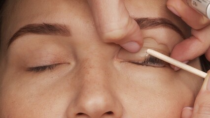 Woman on modern eyelash lamination procedure in a professional beauty salon. Master applies special...