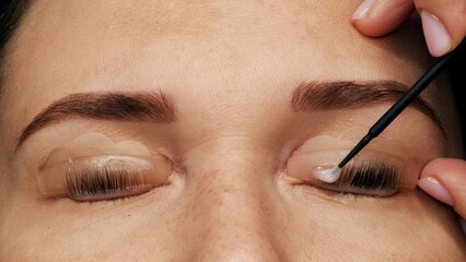 Woman on modern eyelash lamination procedure in a professional beauty salon. Master applies special...