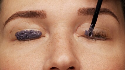 Woman face on modern eyelash lamination procedure in a professional beauty salon. Master applies...