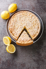 Tasty Sliced Lemon tart sprinkled with icing sugar close-up in a plate on the table. Vertical top view from above