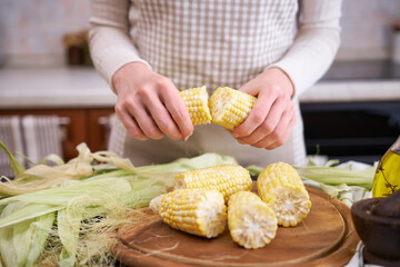 woman holding organic natural corn cob at domestic kitchen