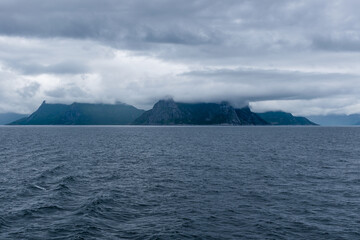 Cloud covered mountains on the shore of Northern Norway. Dramatic seascape in summer, Norwegian sea, Atlantic ocean.