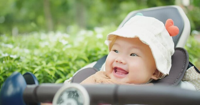 portrait closeup happy little cute Asian baby child toddler enjoy smiling laugh fun in carriage while walking with family at outdoor nature park in summer