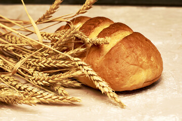 a loaf of bread and ears of wheat on the table