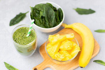 Vegetarian green smoothie with avocado, spinach leaves, pineapple and banana in glass on gray concrete background. Raw, vegan, vegetarian, alkaline food, Healthy Lifestyle detox concept. Selective