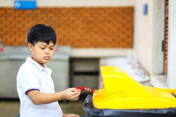 An Asian boy picking up the garbage and putting it in a yellow garbage bag. Ecology protection concept. 