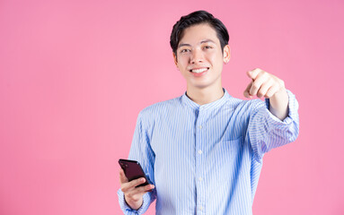 Photo of young Asian man using smartphone on background