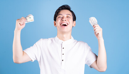 Young Asian man holding money on background