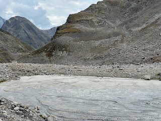 The muddy bottom of a volatile alpine lake below the summit Flüela Wisshorn or Fluela Wisshorn (3085 m) in the Silvretta Alps mountain range, Davos - Canton of Grisons, Switzerland (Kanton Graubünden)