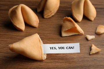 Tasty fortune cookie with prediction Yes, you can! on wooden table, closeup