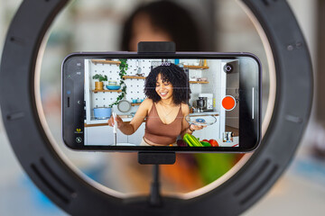 A beautiful African American woman food blogger or vlogger recording a video on smartphone