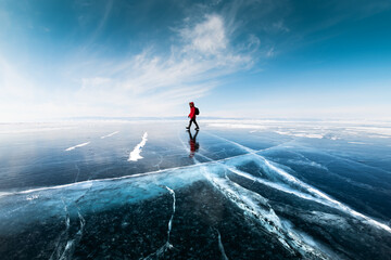 Man tourist walking on the ice of Baikal lake. Winter landscape of Baikal lake, Russia