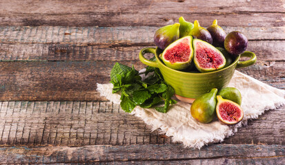 Fresh ripe green figs in a bowl on a wooden background.