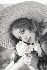 Black and white portrait of stylish girl in straw hat posing on a background of the city.