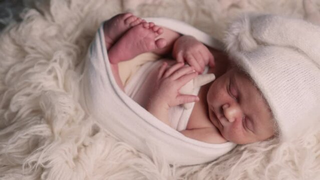 The newborn swaddled boy sleeps sweetly. View from above. Slider camera.