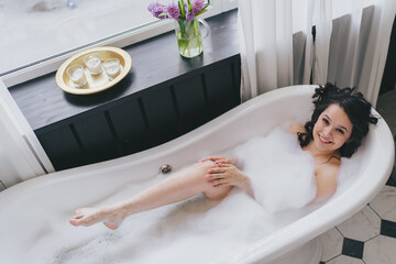 relaxing beautiful woman lying in a spa bath with foam, spa concept. High quality photo