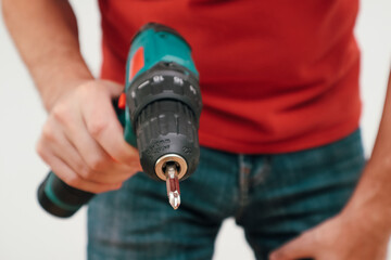 Hand holding cordless drill. Handyman with a tool screwdriver drill.
