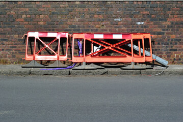 Red and White Plastic Barriers beside Old Brick Wall and Road