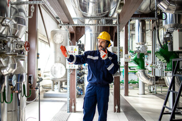 Heating plant worker standing in boiler room and communicating via radio device.