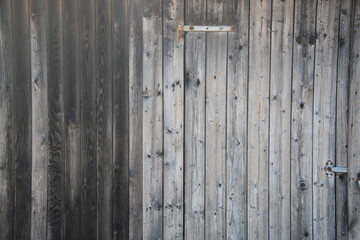 alter Holzverschlag, ungestrichen, grau verwittert mit Metallbeschlägen
