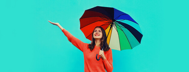 Autumn portrait of happy smiling young woman holding colorful umbrella wearing red knitted sweater...