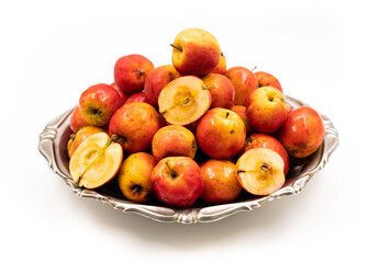 Ripe red small apples Ranetka on a metal plate, on a white background. Isolated background