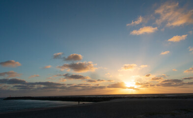 Fototapeta na wymiar Strand Landschaft mit Mole vor bewölkten Himmel während des Sonnenuntergangs