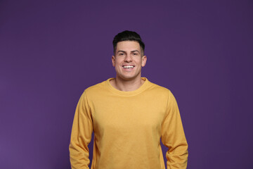 Handsome man laughing on purple background. Funny joke