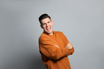 Handsome man laughing on grey background. Funny joke