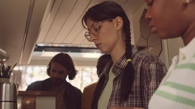 Tilt up shot of two multiethnic girls chatting while making lunch, spending summer weekends with their boyfriends in house on wheels