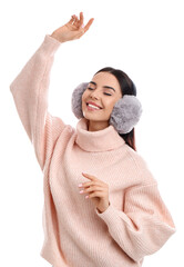 Beautiful young woman wearing earmuffs on white background