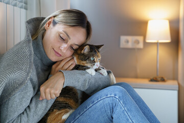 Young woman hugs domestic pet enjoying spending time with favourite cat. Animal makes owner happy and helps to walk through problems and bad thoughts. Female has motivation to make life better