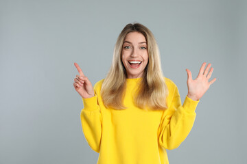 Woman showing number six with her hands on light grey background