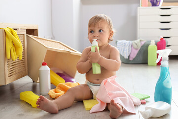Cute baby playing with bottle of detergent on floor at home. Dangerous situation