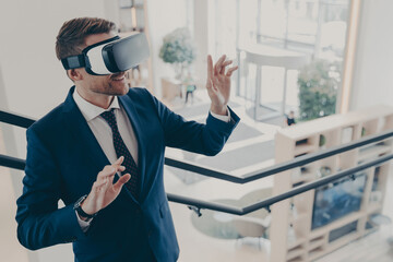 Young businessman wearing virtual reality goggles working in office