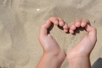 Child holding sand in hands outdoors, closeup with space for text. Fleeting time concept